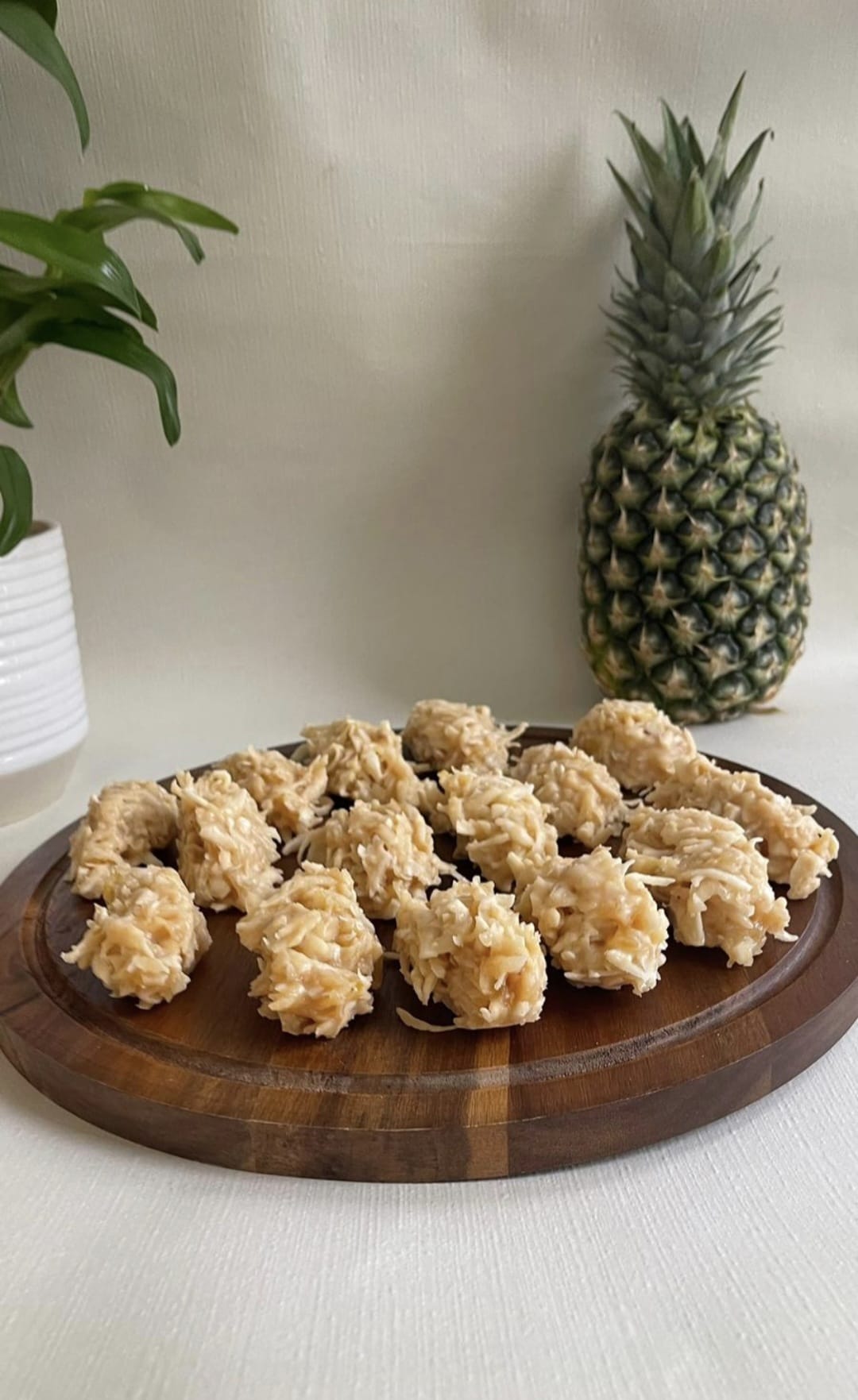 Bolinhas de coco e abacaxi numa tábua redonda de madeira